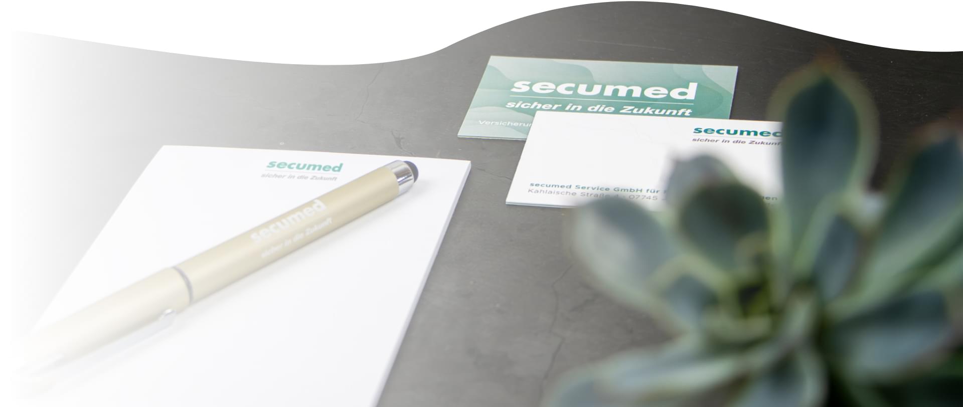 Block mit Stift und Visitenkarte sowie Pflanze Oberfläche